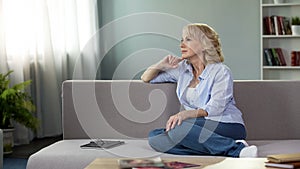 Thoughtful pretty woman relaxing on sofa at home, free time retirement, leisure