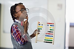 Thoughtful schoolboy using a maths abacus in classroom