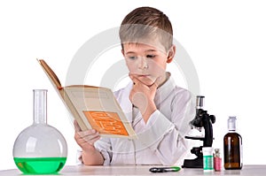 Thoughtful science boy reads book at chemistry lab at the desk