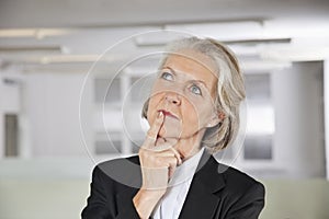 Thoughtful senior businesswoman looking up in office