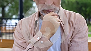 Thoughtful senior man sitting on park bench, retirement age, serious decision