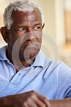 Thoughtful Senior Man Sitting On Sofa At Home