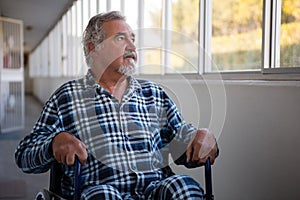 Thoughtful senior man sitting on wheelchair in nursing home