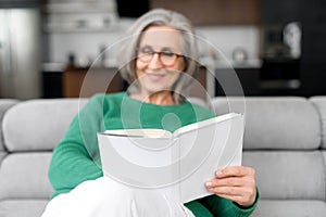 Thoughtful senior woman holding and reading a book