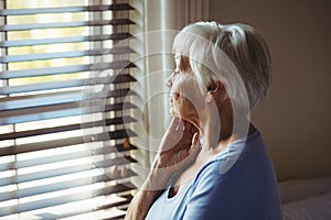 Thoughtful senior woman looking out from window