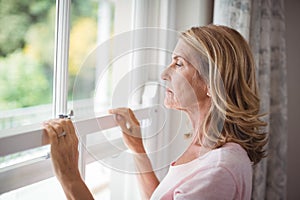 Thoughtful senior woman looking out from the window