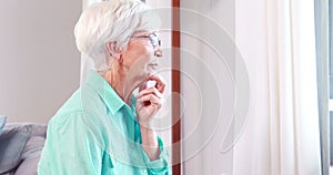 Thoughtful senior woman looking through window