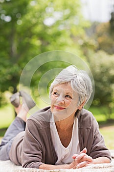 Thoughtful senior woman lying at park