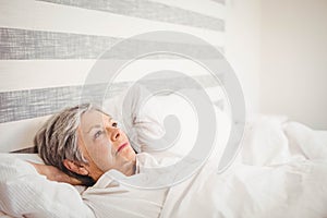 Thoughtful senior woman relaxing on bed