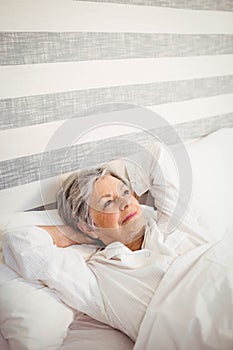 Thoughtful senior woman relaxing on bed