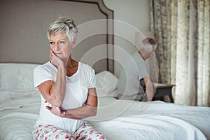 Thoughtful senior woman sitting in bed room