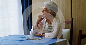 Thoughtful senior woman sitting at table 4k