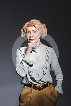 thoughtful senior woman in stylish shirt looking at camera