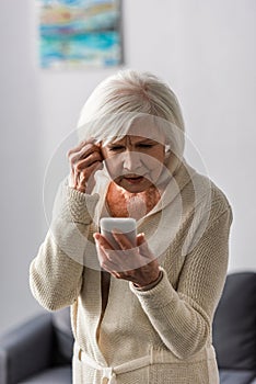 Thoughtful senior woman touching head while