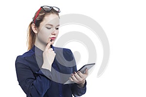 Thoughtful serious young red-haired woman in a blue blouse and glasses with a tablet. Isolated on white background. Space for text