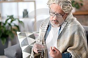 Thoughtful sick senior man taking medication