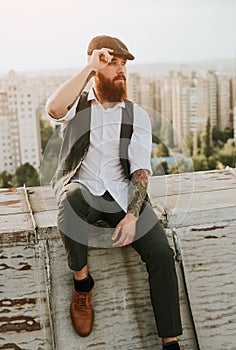 Thoughtful stylish man sitting on rooftop