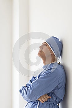 Thoughtful Surgeon With Arms Crossed Leaning On Wall