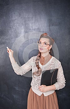Thoughtful teacher in glasses with piece of chalk