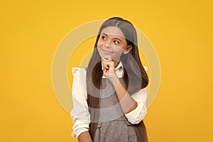 Thoughtful teenage child girl on yellow background. Portrait of a kid thinking over idea. Pensive girl. Thinking face