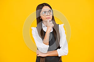 Thoughtful teenage child girl on yellow background. Portrait of a kid thinking over idea. Pensive girl. Thinking face
