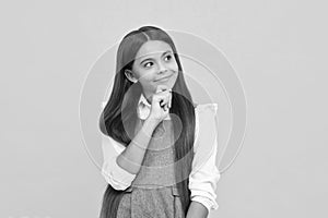 Thoughtful teenage child girl on yellow background. Portrait of a kid thinking over idea. Pensive girl. Thinking face