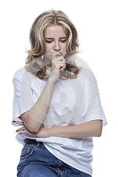 Thoughtful teenage girl. Pretty blonde girl in a white t-shirt and jeans. Negative emotions and loneliness in puberty. Isolated on