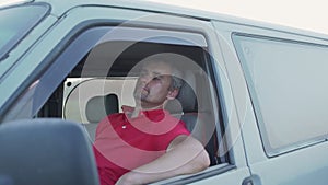 Thoughtful tired man resting at minivan putting his hand on open side window