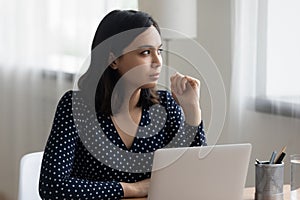 Thoughtful vietnamese female look aside of laptop visualize work result