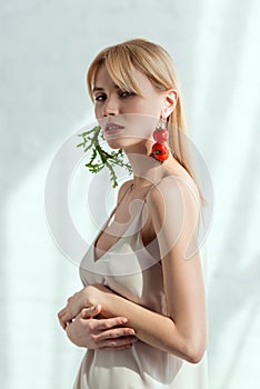 thoughtful woman in dress with earrings made of fresh arugula and cherry tomatoes vegan