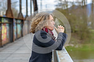Thoughtful woman gazing out from a bridge photo
