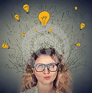 Thoughtful woman in glasses with many ideas light bulbs above head