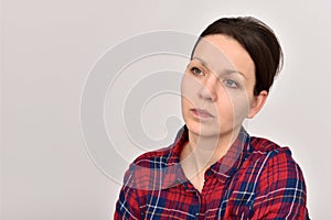 Thoughtful woman with hair bun wearing a tartan shirt