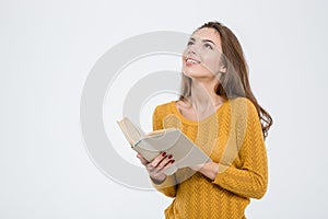 Thoughtful woman holding book and looking up