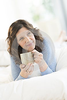 Thoughtful Woman Holding Coffee Mug In Bed