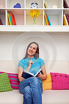 Thoughtful woman holding pen and notebook