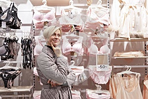 A thoughtful woman in a lingerie store is having a hard time making a choice. Fashion and beauty