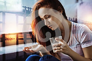 Thoughtful woman looking at the pills and holding a glass of water