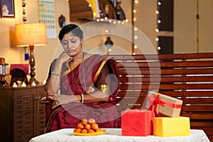 thoughtful woman or mother waiting for kids or relatives for diwali festival celebration at home - concept of negative