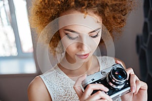 Thoughtful woman photographer holding vintage camera