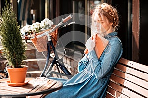 Thoughtful woman readng book and dreaming on the beanch outdoors