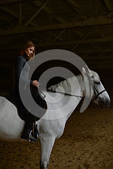 Thoughtful woman rides white horse.
