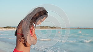 Thoughtful woman staying at coastline. Focused girl hugging herself at beach.
