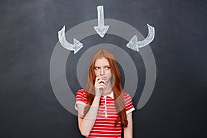 Thoughtful woman thinking over blackboard background with drawn arrows