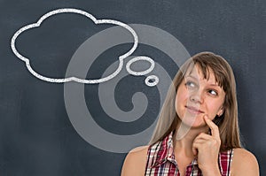 Thoughtful woman with thought bubble on blackboard