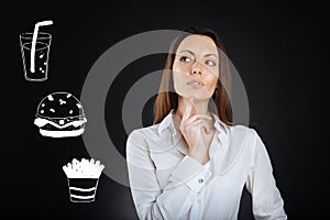 Thoughtful woman touching her chin while choosing food in a cafe
