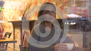 Thoughtful woman watching passersby through window of her favorite coffee house