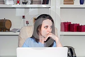 Thoughtful woman working on computer looking away thinking solving problem