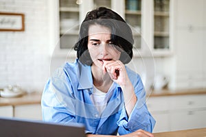 Thoughtful woman working at laptop and think about project photo