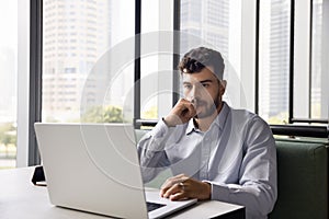 Thoughtful young Arab manager man working at laptop